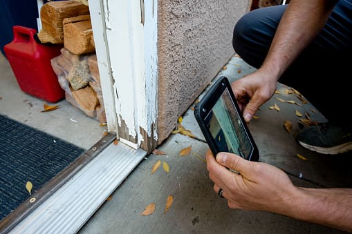 Property Inspector Photographing an Exterior Door Frame with Damaged and Missing Paint